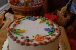fall themed cake with pumpkin, grapes and corn decorated in icing