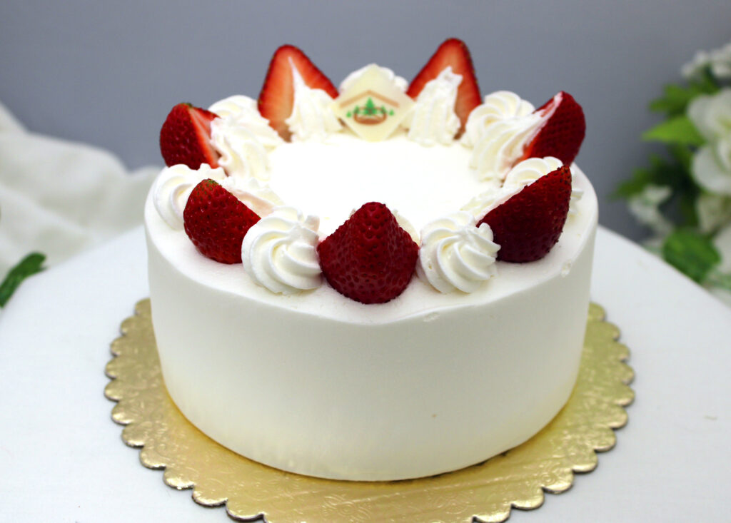 Vanilla Sponge Cake with Strawberry Filling, Whipped Cream Icing, topped with Fresh Strawberries.